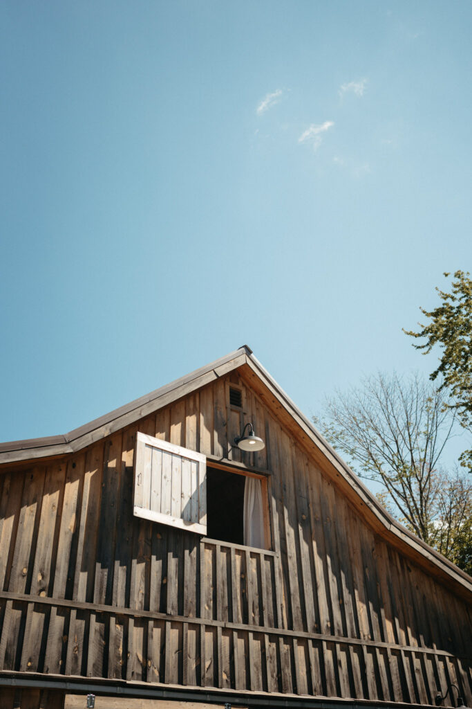 Weathered barn with an open hayloft window under a blue sky
