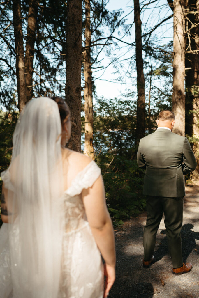 Person in a veil walking up behind a person in a green suit on a forest path
