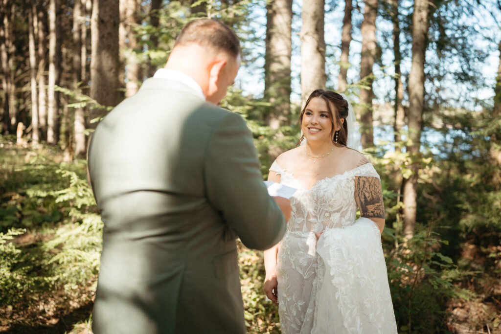 Couple reading notes to each other in the woods, one with their back to the camera