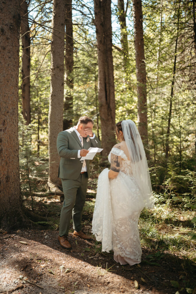 Couple reading notes in a forest, one wiping their eye