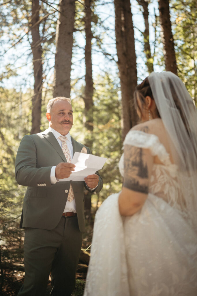 Person in a green suit reading a note to a person in a lace gown