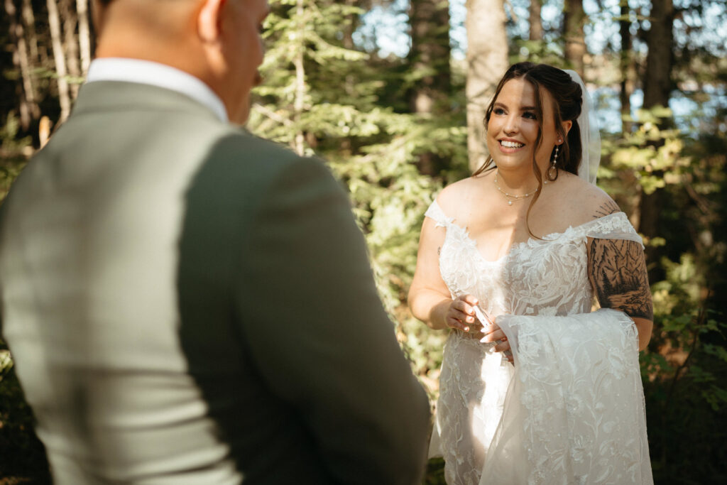 Person in a lace gown smiling at a person in a green suit, seen from behind