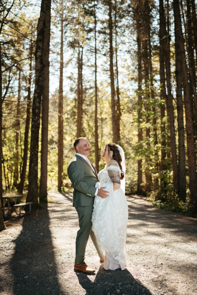 Couple dancing on a gravel path lined with tall trees