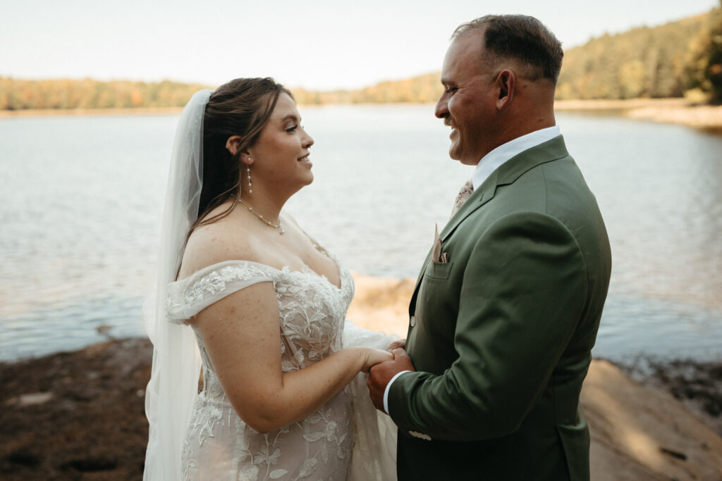 Couple holding hands and smiling at each other beside a lake