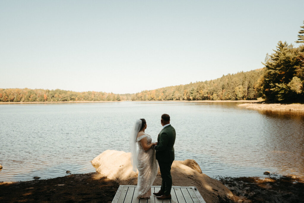 Couple standing on a small dock facing a lake