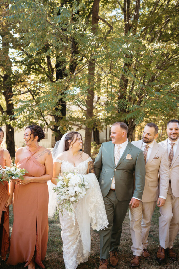 Couple walking with their wedding party among trees