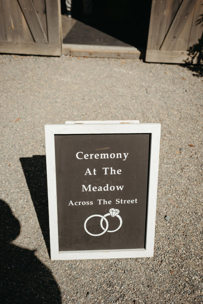 Sign reading Ceremony At The Meadow Across The Street, with a rings graphic