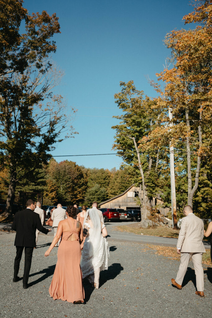 Guests walking up a gravel drive toward the barn after the ceremony