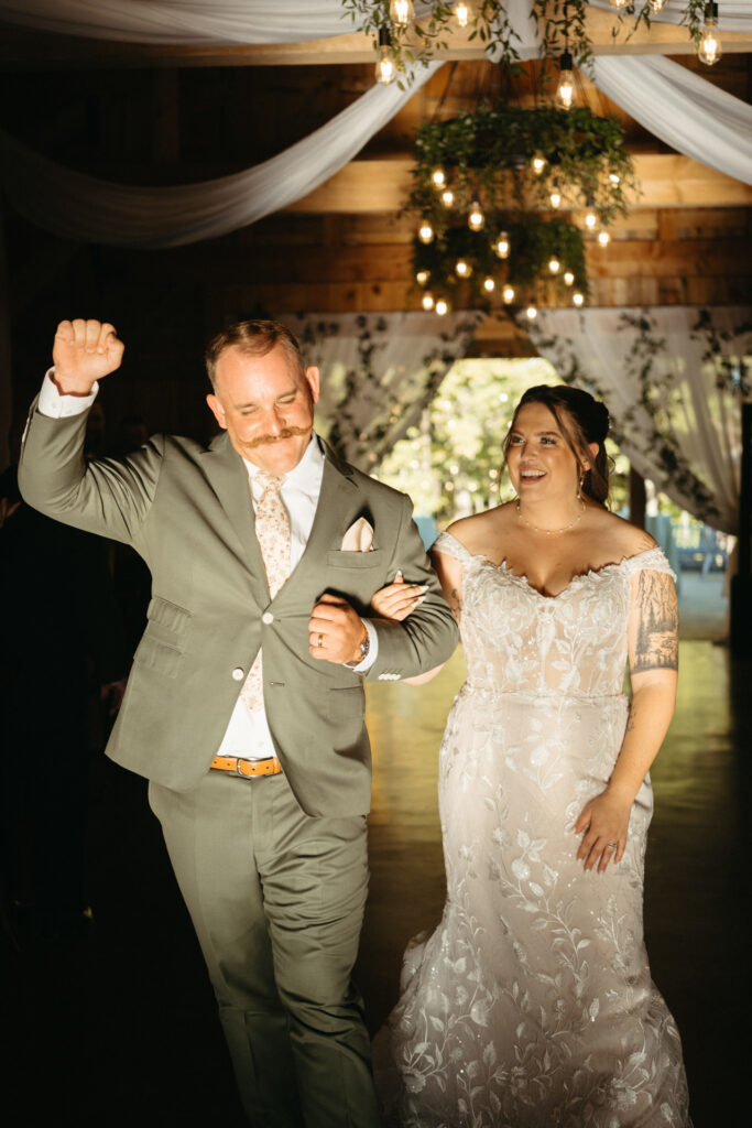 Couple entering the barn reception, one with a raised fist