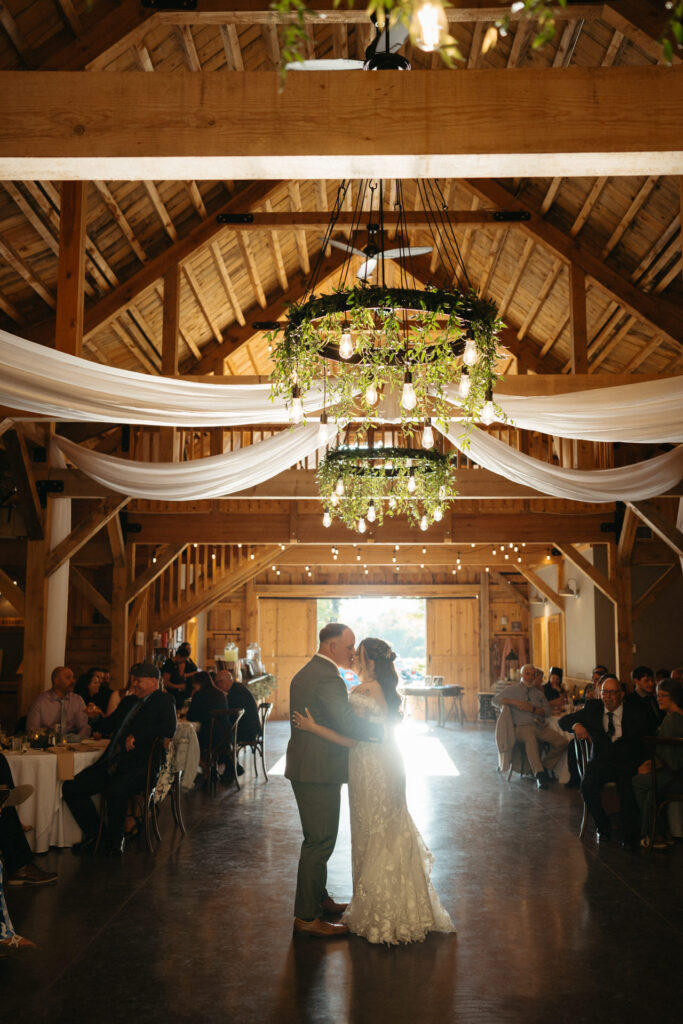 Couple dancing in the barn reception under chandeliers