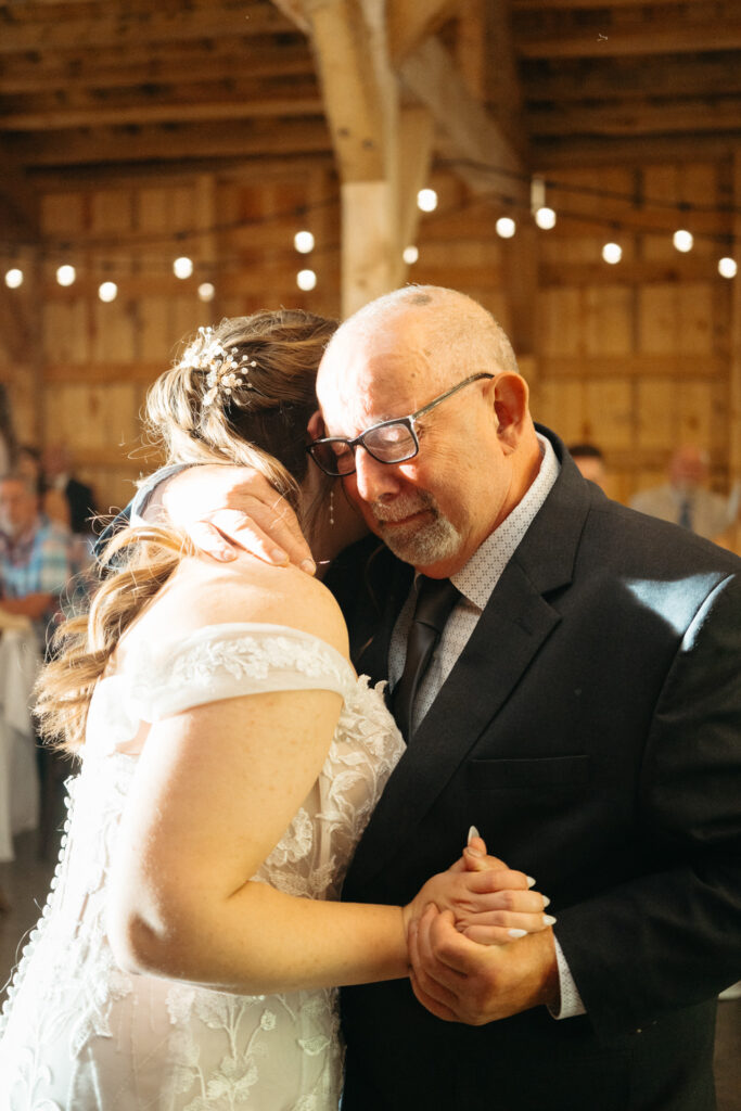 Person in a lace gown dancing with a person in a dark suit, both emotional