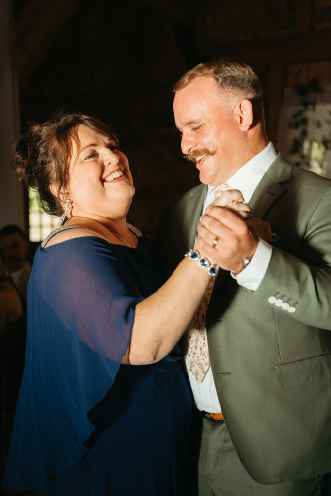 Person in a green suit dancing with a person in a blue top, both laughing