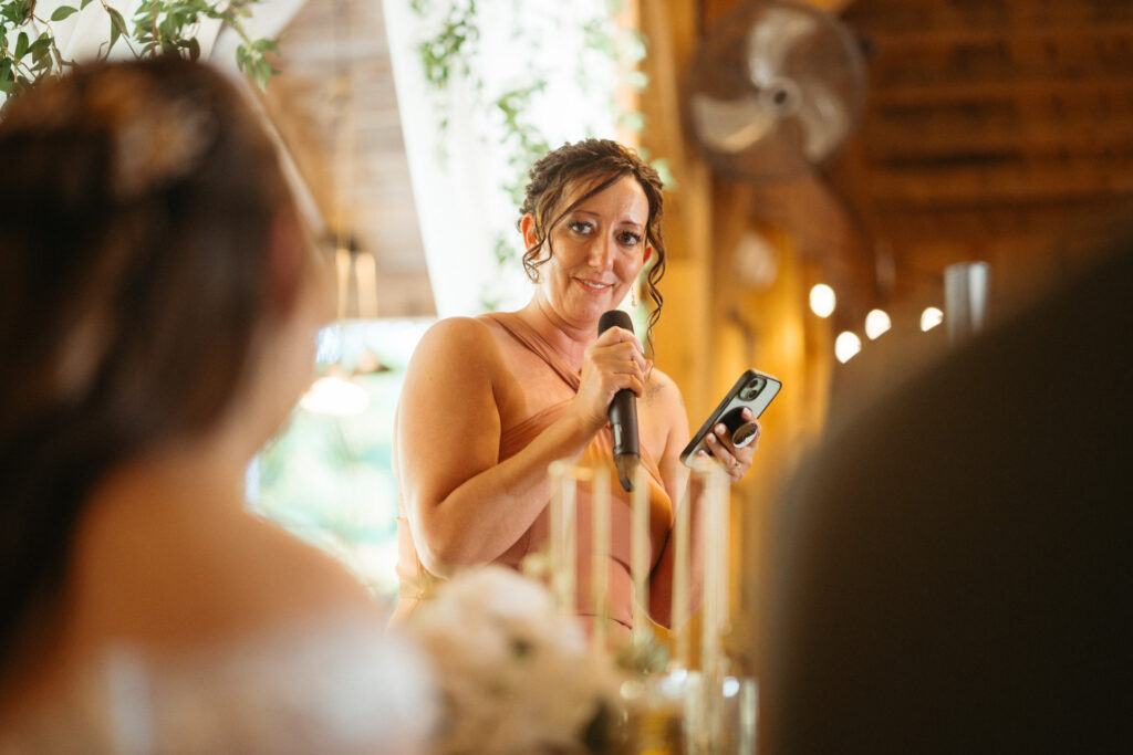 Guest giving a toast into a microphone, the couple in the foreground