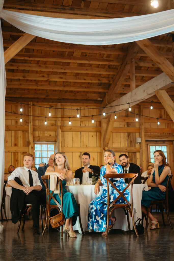 Guests seated at round tables in the barn