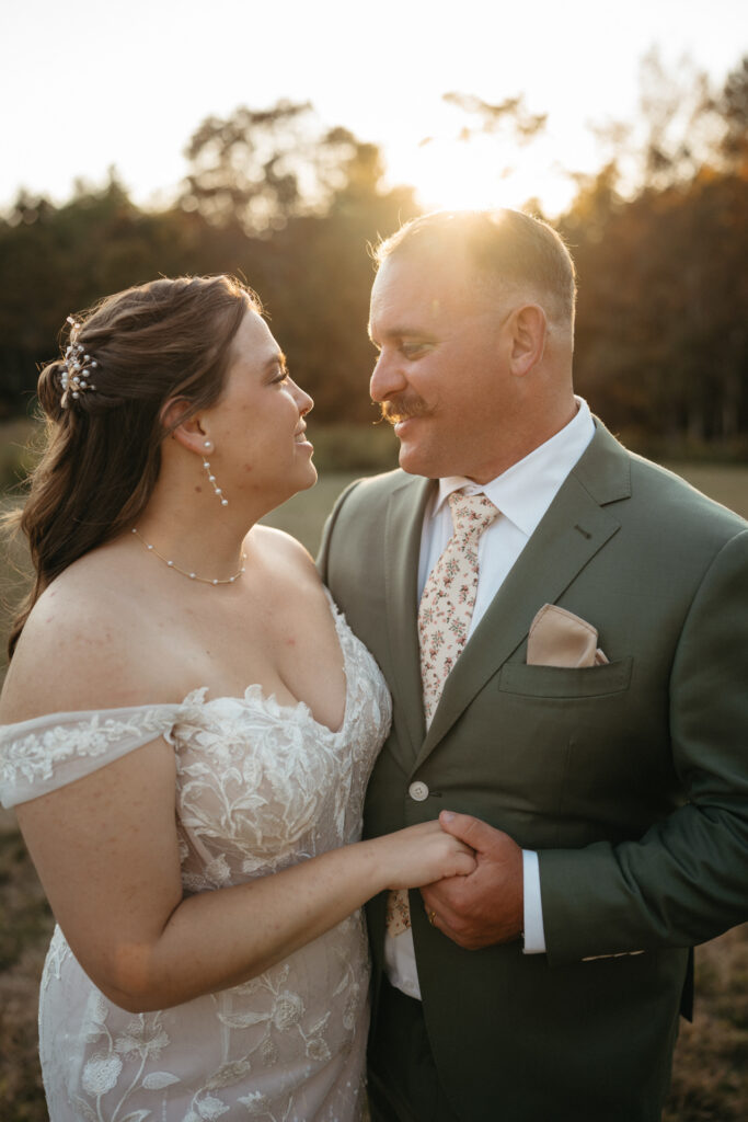 Couple holding hands and smiling at each other in golden light