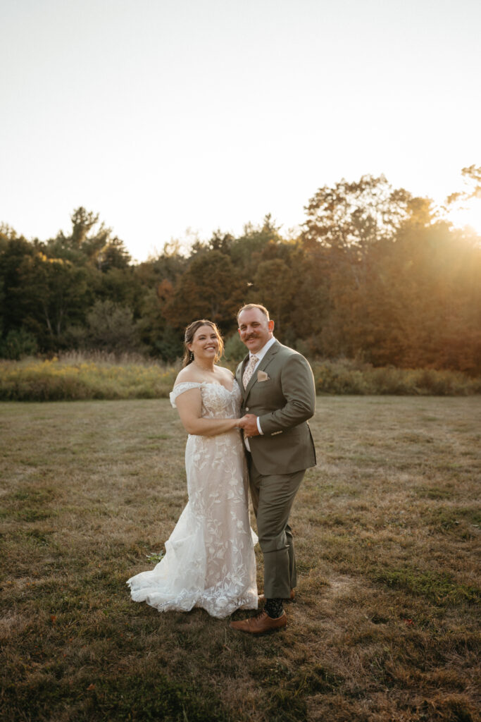 Couple standing close in a field at sunset