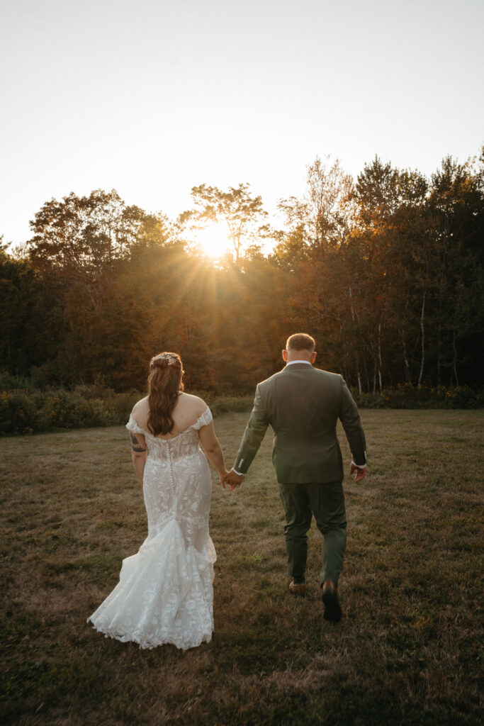 Couple walking toward the setting sun through a field, seen from behind