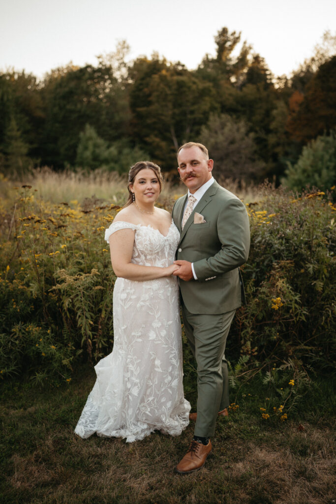 Couple standing together in front of tall wildflowers
