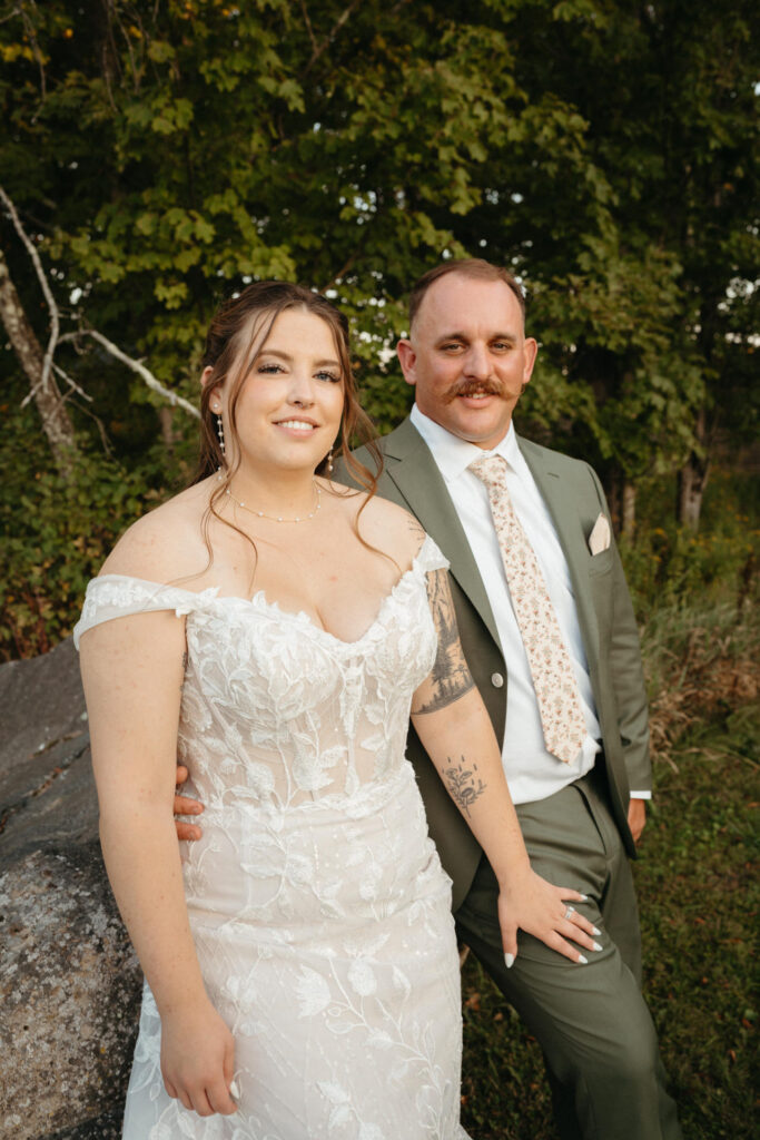 Couple leaning against a boulder and smiling at the camera