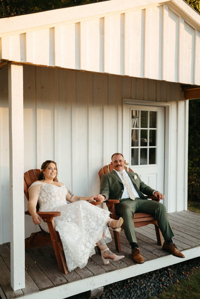 Couple relaxing in Adirondack chairs on the porch of a white shed