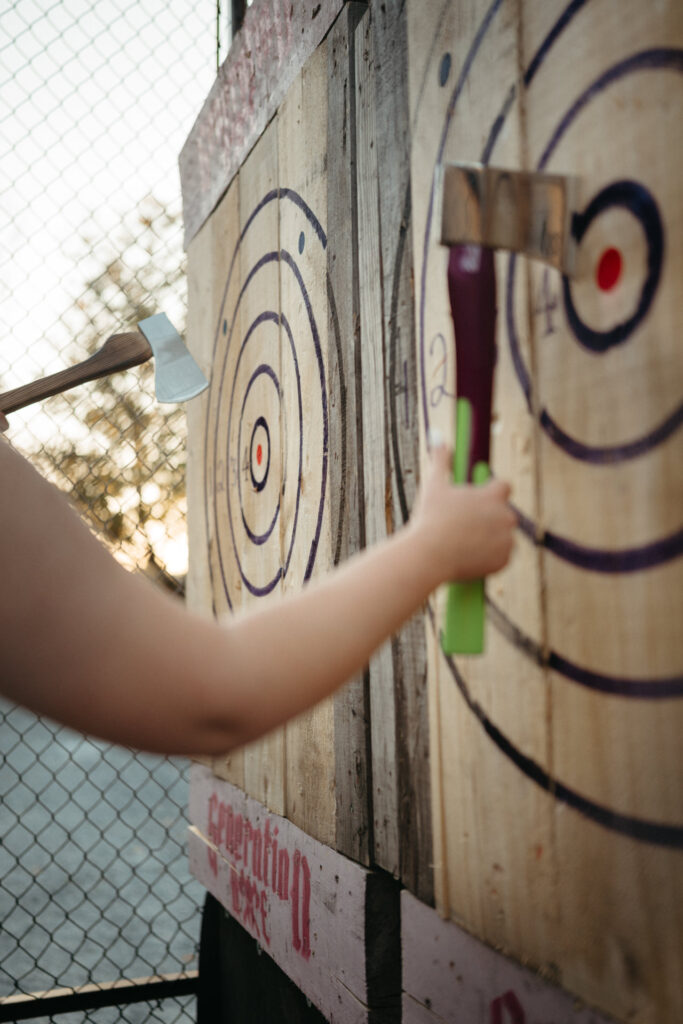 Hand throwing an axe at a target board