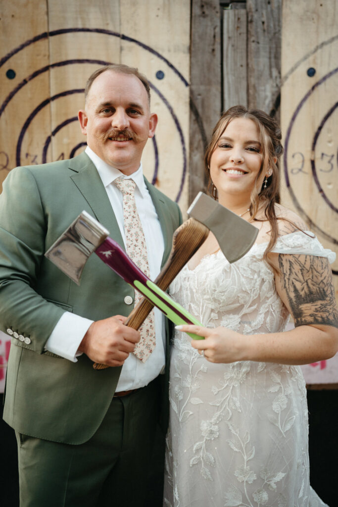 Couple holding axes and smiling in front of target boards