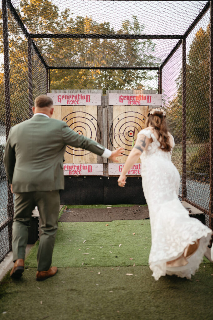 Couple at the axe throwing trailer, one winding up a throw