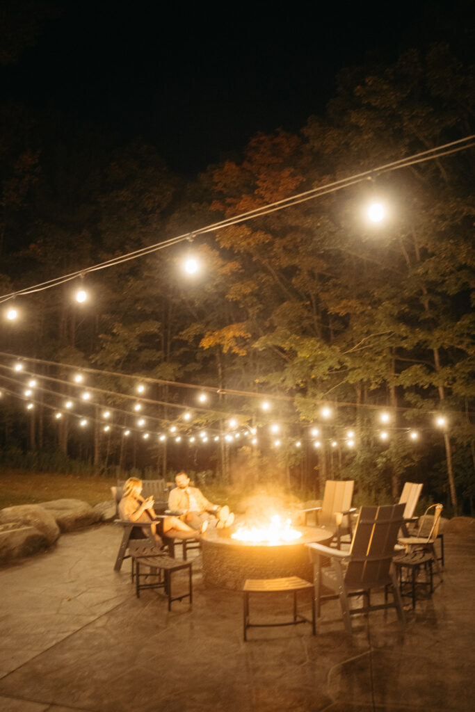 Fire pit with chairs under string lights at night