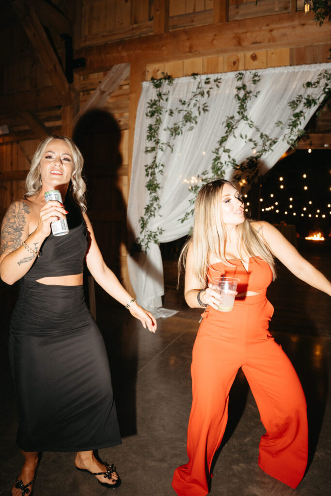 Two guests dancing with drinks in the barn