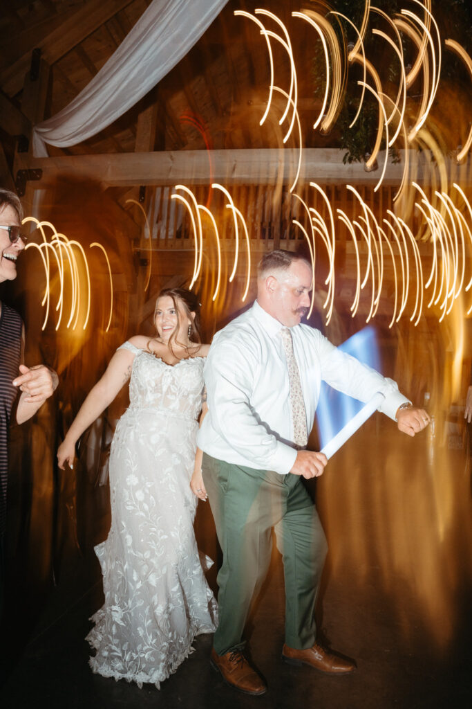 Couple dancing with glow sticks, light trails streaking behind them