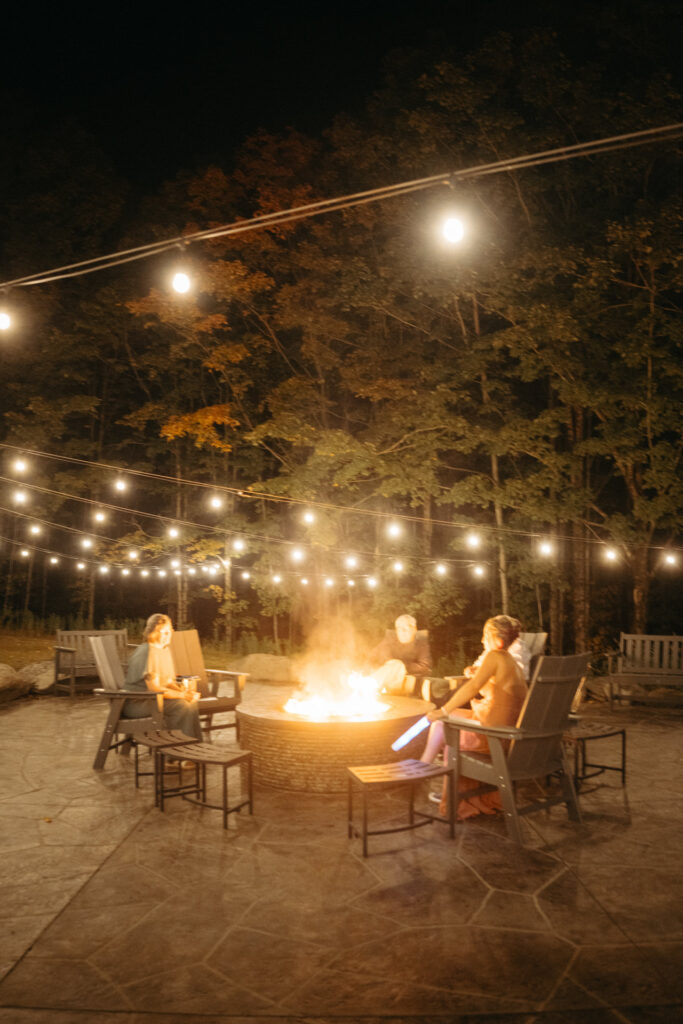 Fire pit and chairs under string lights at night