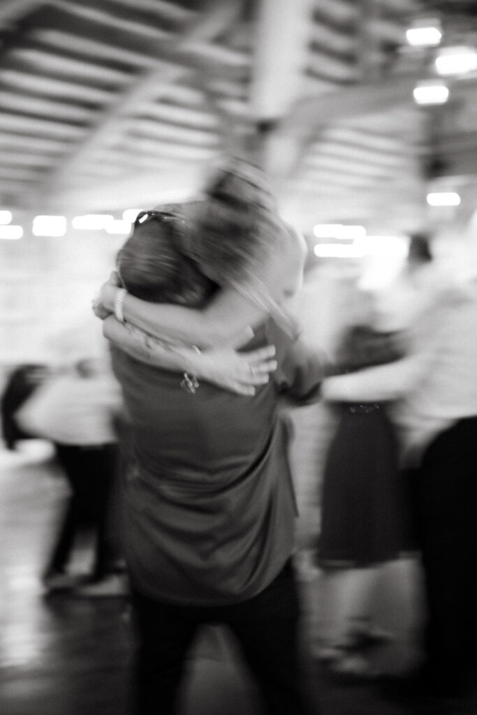 Black and white blurred photo of guests hugging on the dance floor