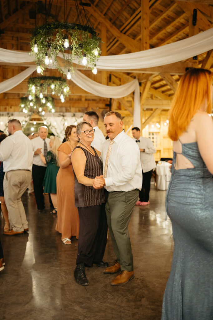 Guests dancing in the barn under chandeliers and draped fabric