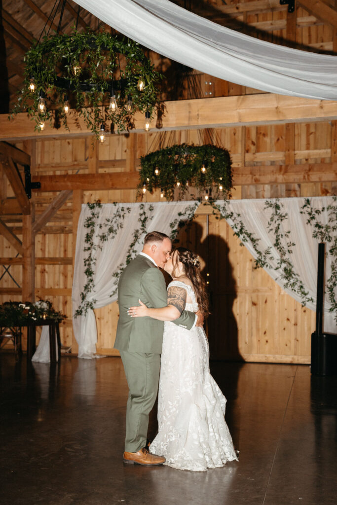 Couple kissing on the dance floor in front of a draped doorway