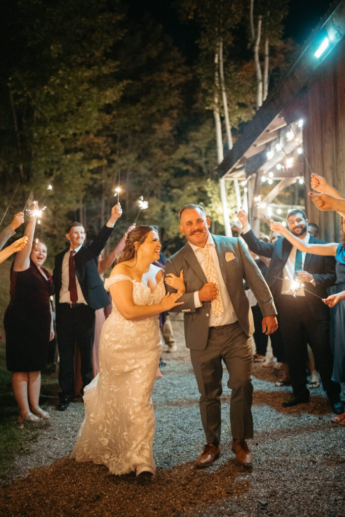 Couple walking hand in hand between guests holding sparklers