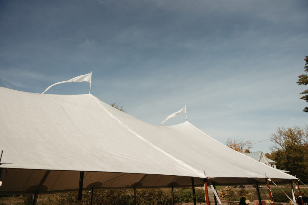 White tent with flags under a blue sky