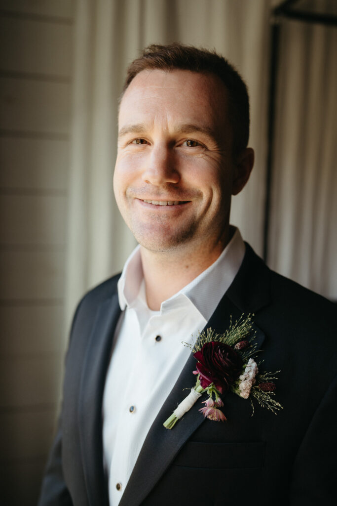 Close-up of a smiling person in a tuxedo with a boutonniere