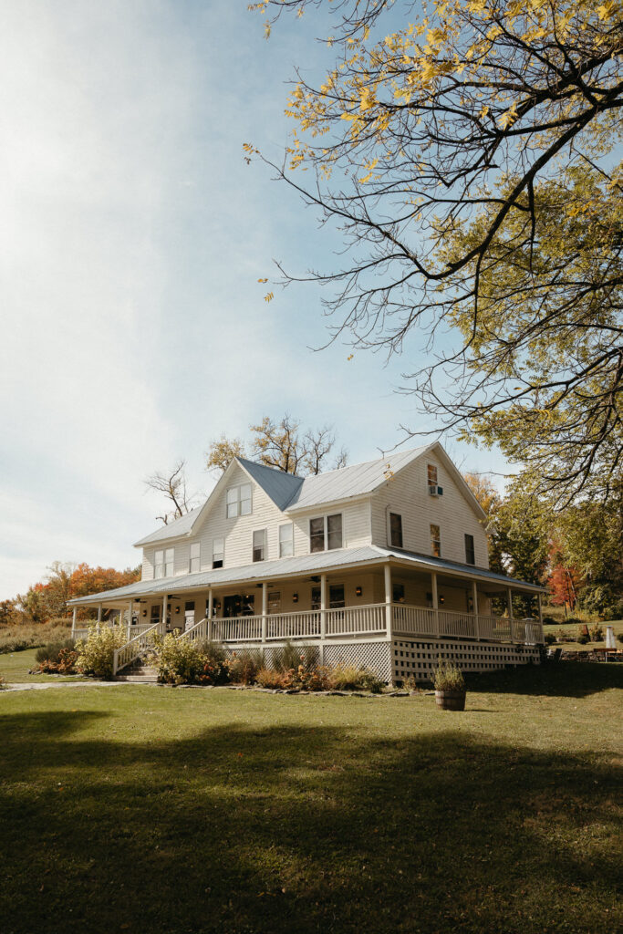 White farmhouse with a wraparound porch on a lawn
