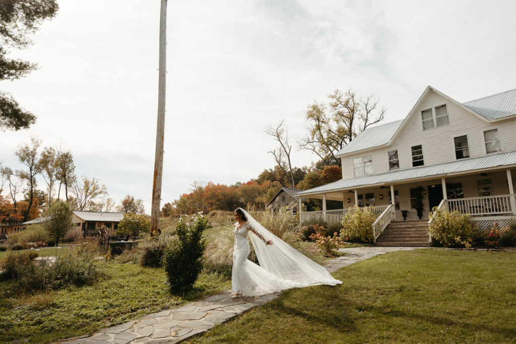 Person in a veil walking up a stone path toward the farmhouse