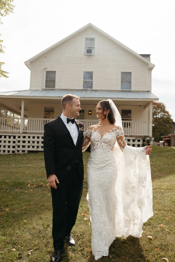 Couple standing close in front of the farmhouse, one holding up the train