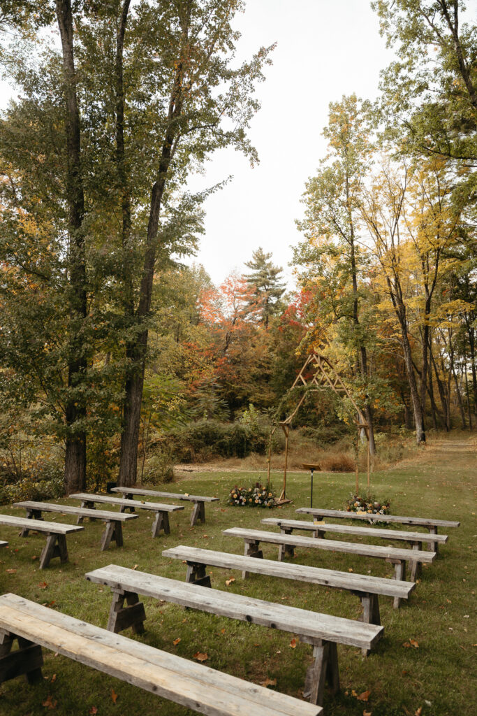 Rows of wooden benches set for the ceremony in the woods