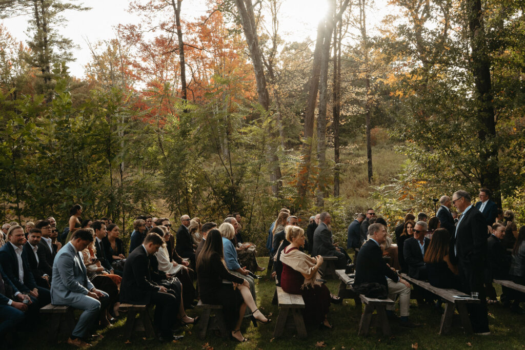 Guests seated on benches at the ceremony in the woods