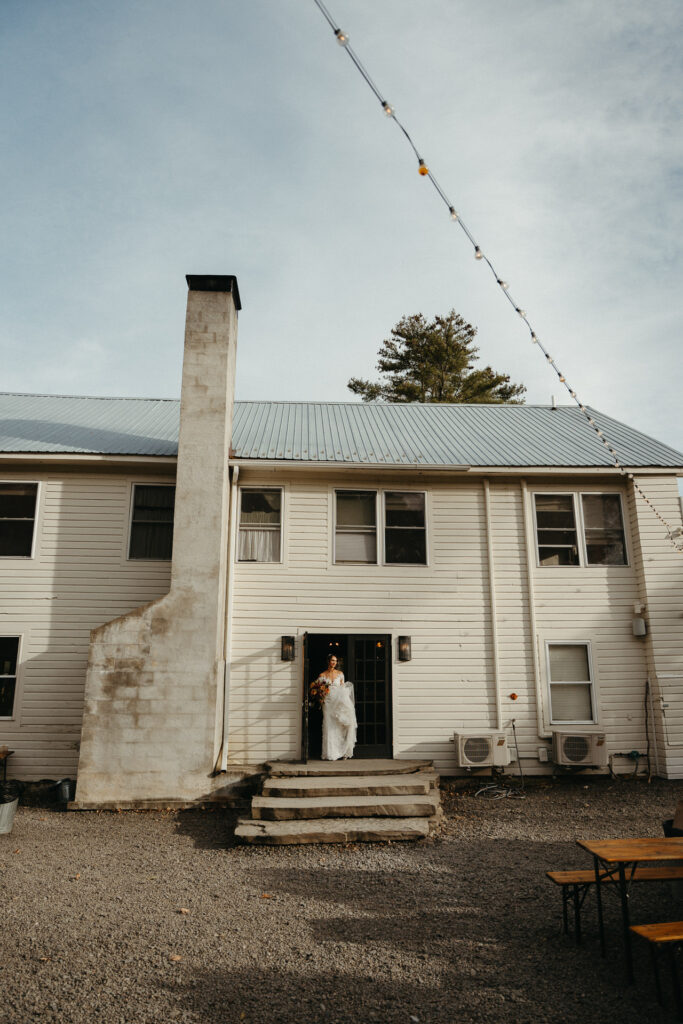 Person in a gown standing in the farmhouse doorway