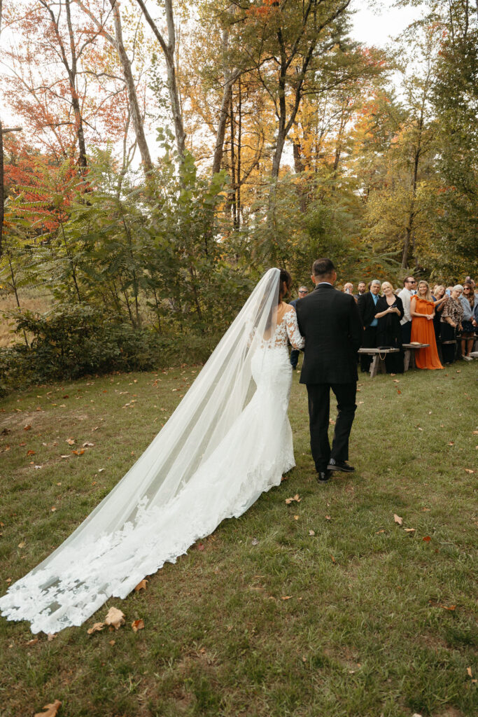 Person in a long veil walking down the aisle behind an escort