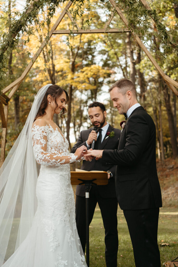 Couple exchanging rings under the arch with the officiant