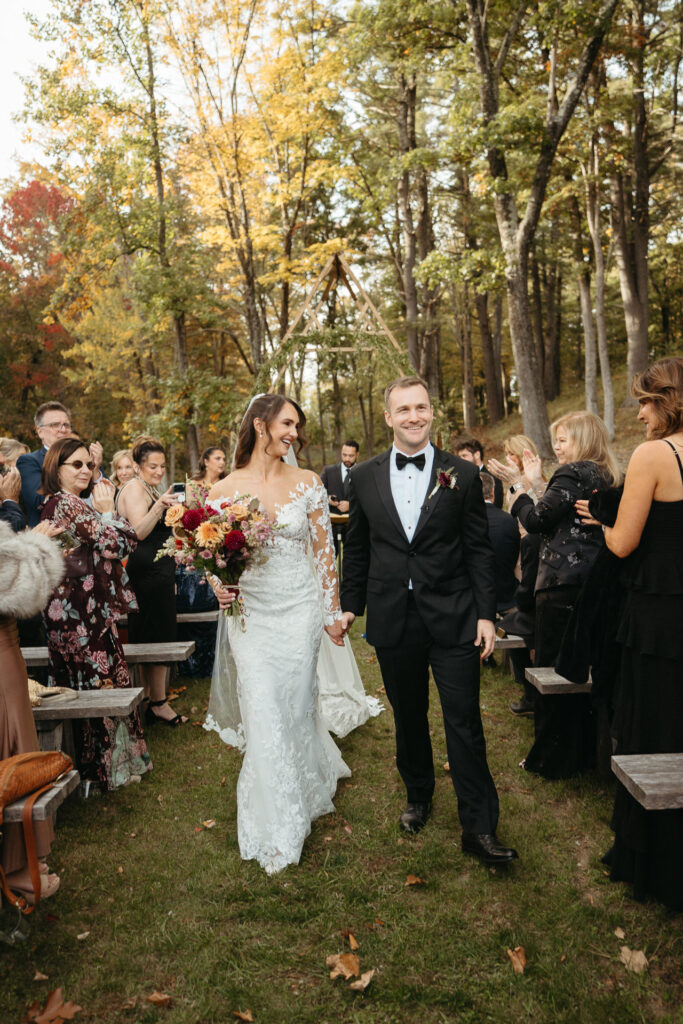 Couple walking back down the aisle smiling as guests cheer