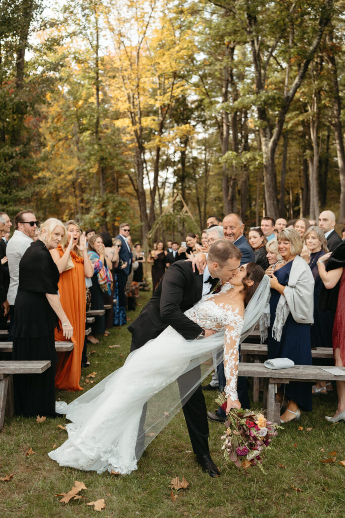 Couple dipping for a kiss in the aisle as guests watch