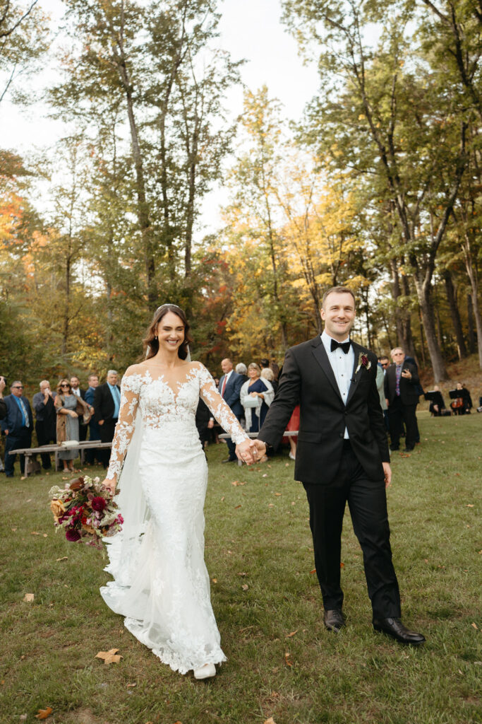 Couple holding hands and walking across the lawn after the ceremony