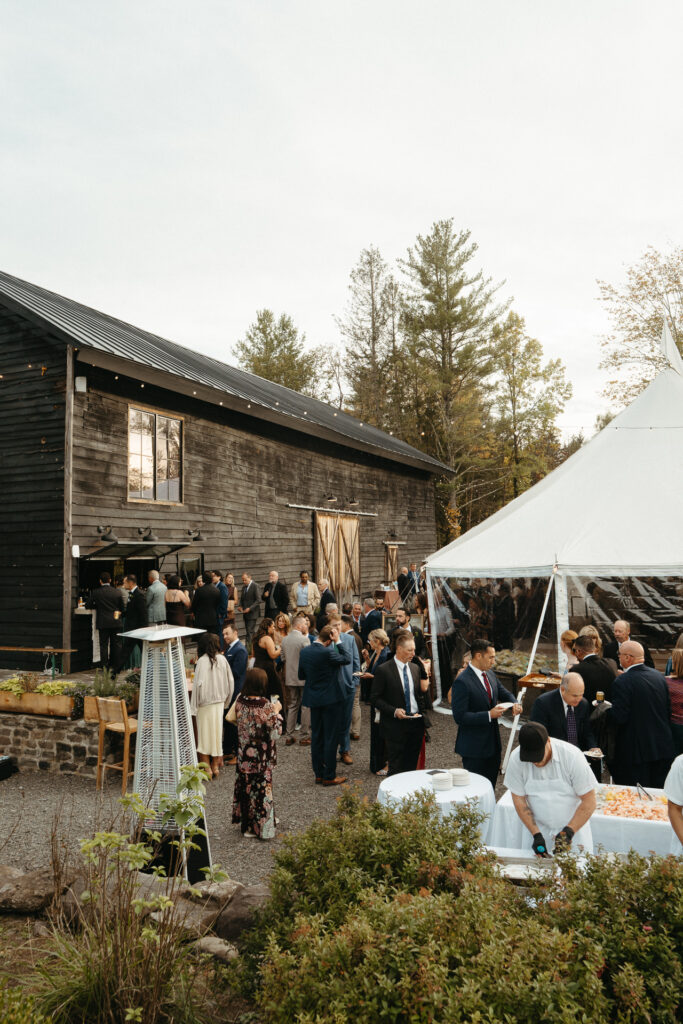 Barn and white tent with guests gathered for cocktail hour