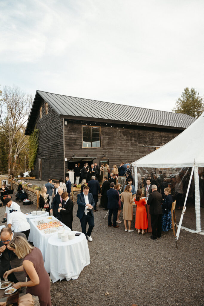 Gray barn and white tent with guests gathered for cocktail hour